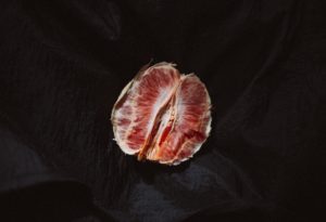 alt text: image is a color photograph of a peeled orange; title card for Stella Lei's short story "Graftings"