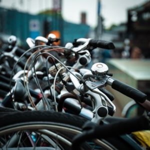 alt text: image is a color photograph of a bicycle's handlebars and bell; title card for the flash fiction piece "What the Mouth Knows" by Amina Gautier