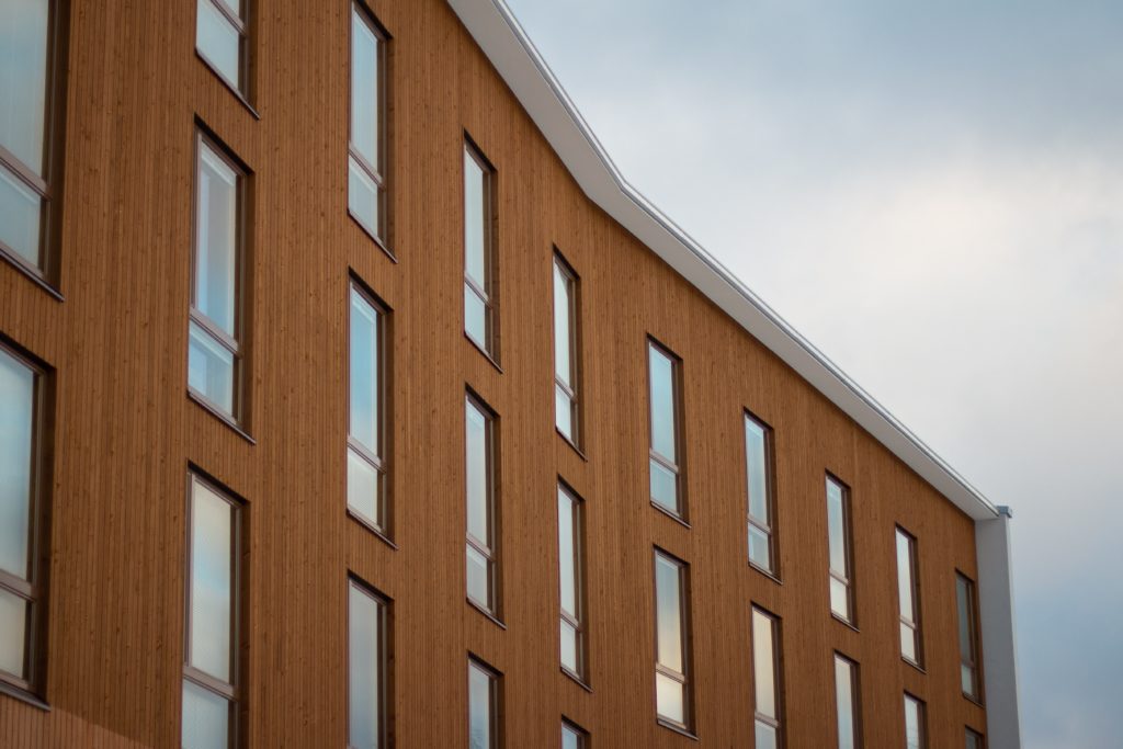 alt text: image is a color photograph of a wood paneled apartment building; title card for the creative nonfiction piece "Deaf Rage" by Ross Showalter