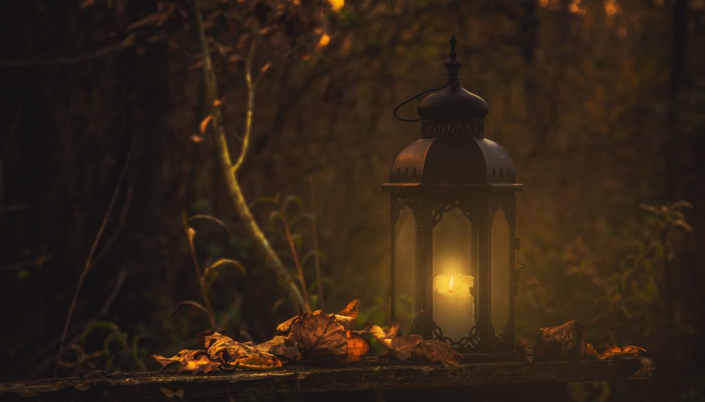 alt text: image is a color photograph of a lantern surrounded by autumn leaves; title card for the short story "The Witch Hare" by AJ Strosahl