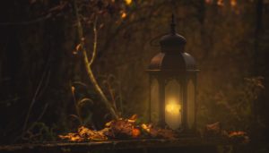 alt text: image is a color photograph of a lantern surrounded by autumn leaves; title card for the short story "The Witch Hare" by AJ Strosahl
