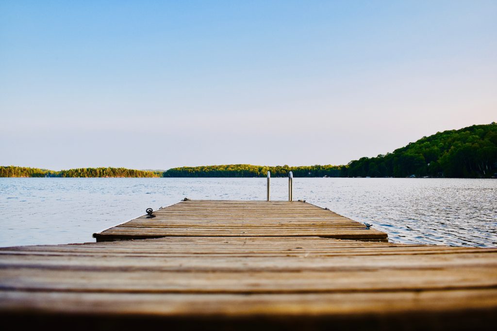 alt text: image is a color photograph of a deck overlooking the water; title card for the short story "Late Summer" by Isabella Barrengos,