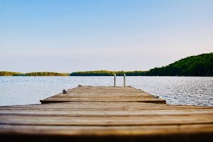 alt text: image is a color photograph of a deck overlooking the water; title card for the short story "Late Summer" by Isabella Barrengos,