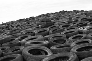 alt text: image is a photograph of black tires in a matrix against a white background; title card for the craft essay "Wisdom and Wisdom Teeth: Against Relatability" by Karen Babine