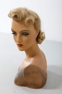 Image is a photograph of a blonde mannequin's head and hairstyle.